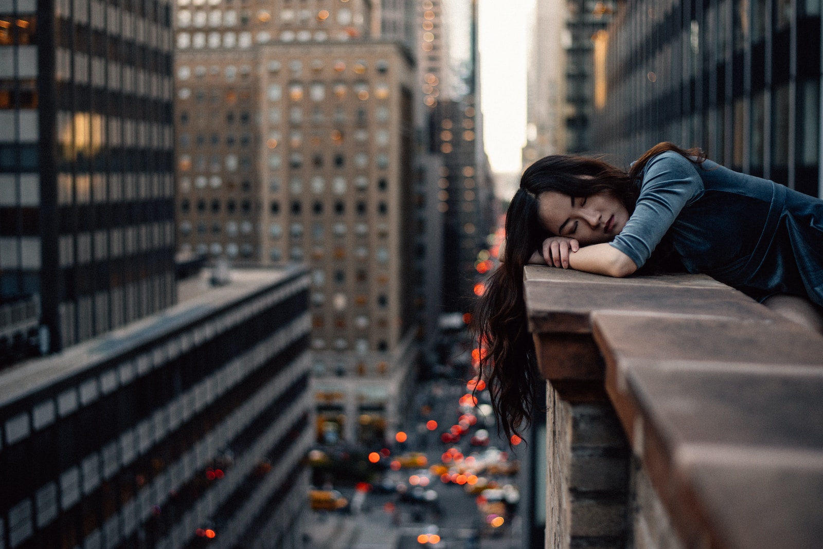 woman asleep leaning on top building rail during daytime